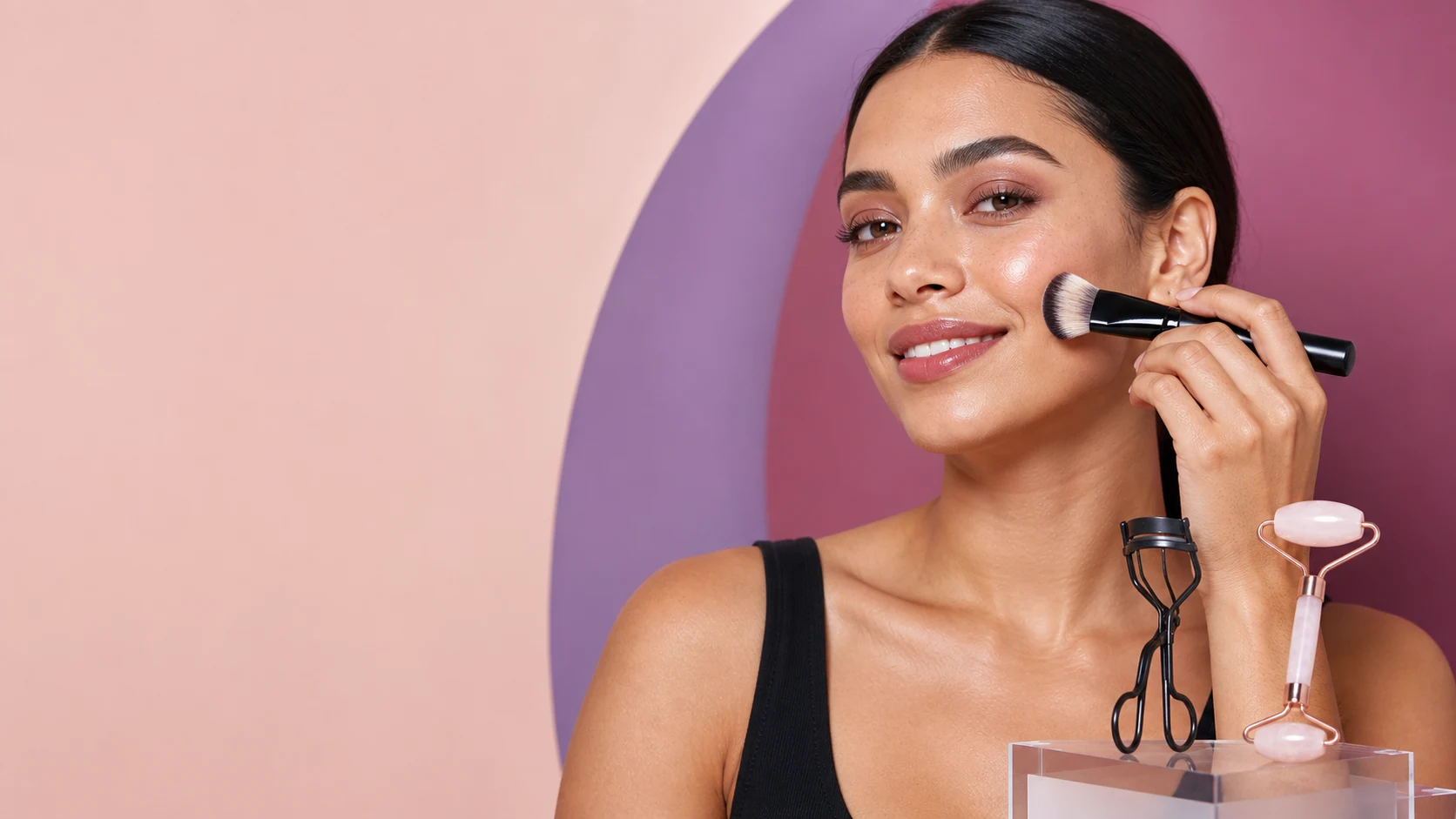 Adult model applying makeup with a complexion brush beside an eyelash curler and rose quartz roller
